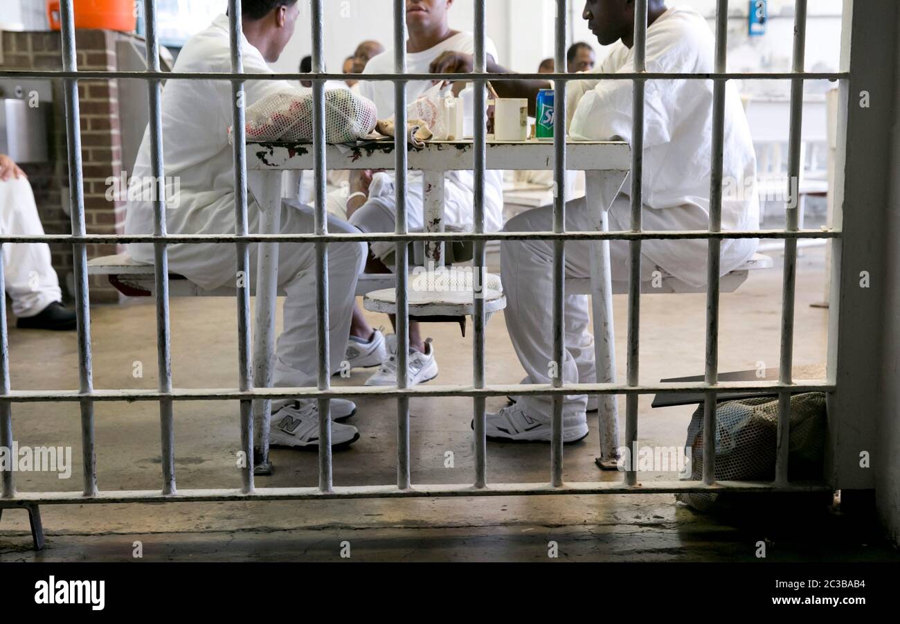 Rosharon Texas USA, August 26 2013: Inmates wearing white uniforms gather behind bars in common area where they are allowed to socialize. They are incarcerated in Darrington Prison, a maximum-security unit of the Texas Department of Criminal Justice. ©Marjorie Kamys Cotera/Daemmrich Photography Stock Photo