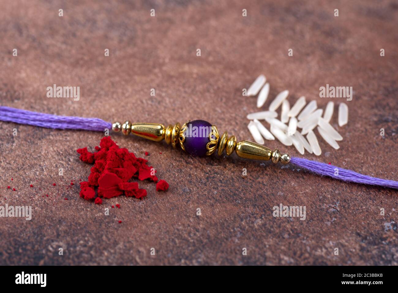 Raksha Bandhan : Rakhi with rice grains and kumkum on stone background ...