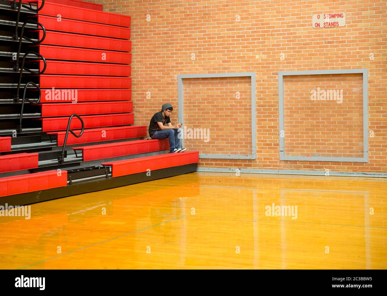 Hispanic high school senior student uses mobile phone to text as he