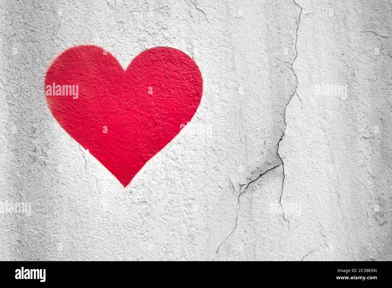 Red love heart hand drawn on grungy wall. Textured background trendy street style. Copy space. Stock Photo