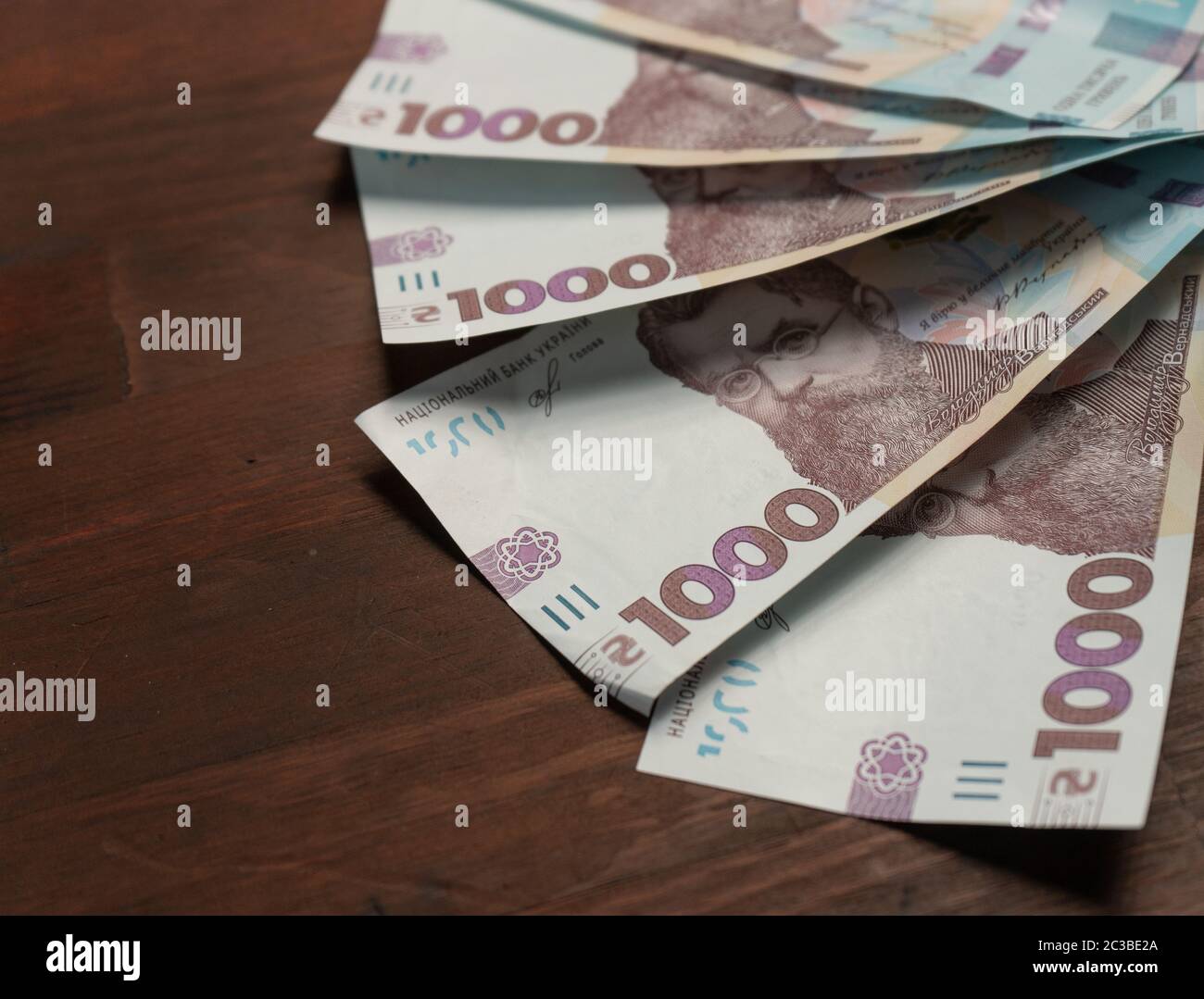 New Ukrainian paper money face value thousand hryvnia in semicircle on wooden back with empty cpace at left. Selective focus in centre of image. Close Stock Photo