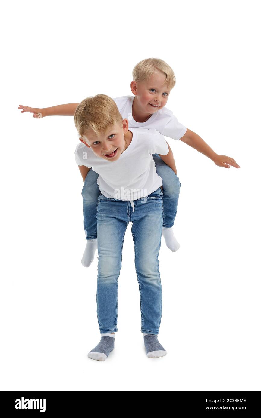 Friendly family. Older brother is carrying younger boy on the back ,  isolated on a white background. Happy siblings. Two little brothers.  Concept of Stock Photo - Alamy