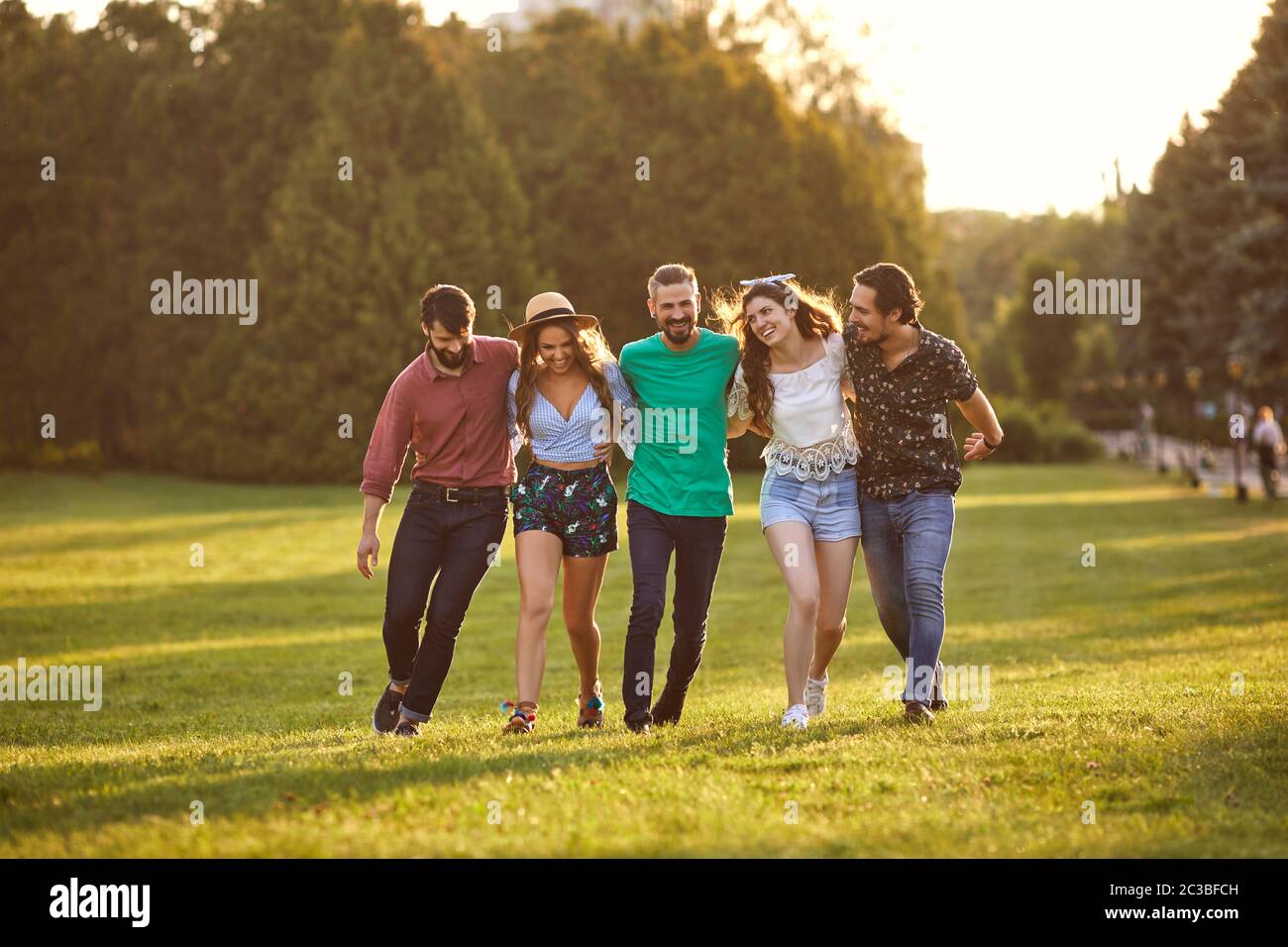 Group of friends hugging during their walk in countryside on summer day. Cheerful people enjoying their weekend outside Stock Photo