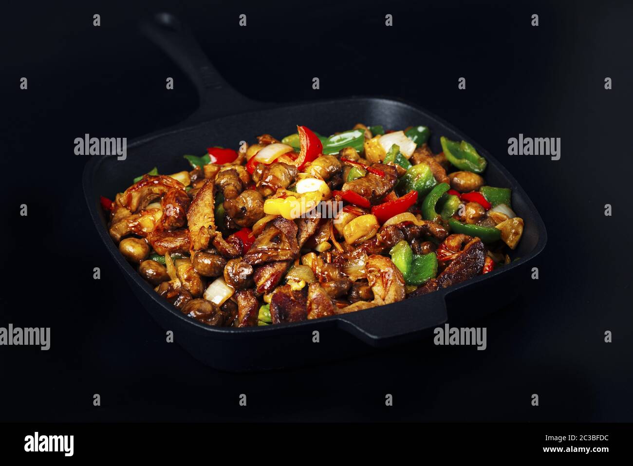 Fried meat and vegetables in cast iron pan Stock Photo