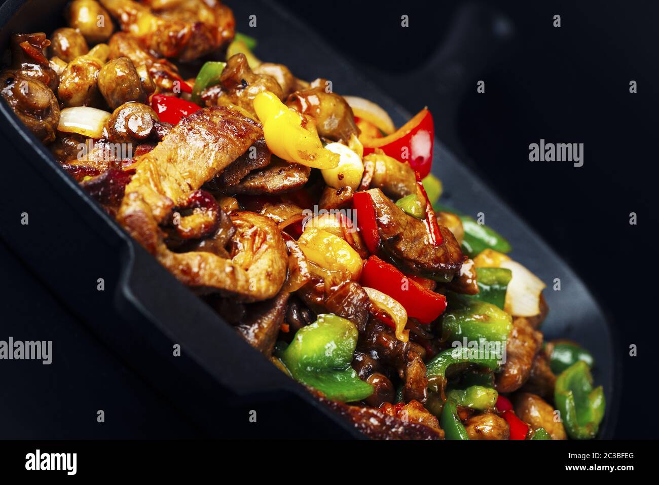 Fried meat and vegetables in cast iron pan Stock Photo