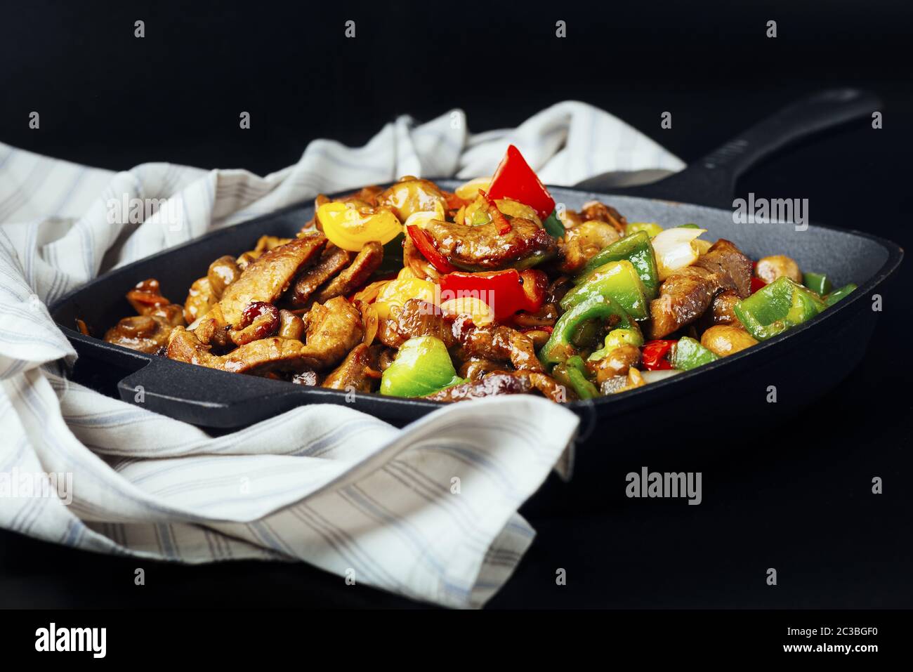 Fried meat and vegetables in cast iron pan Stock Photo