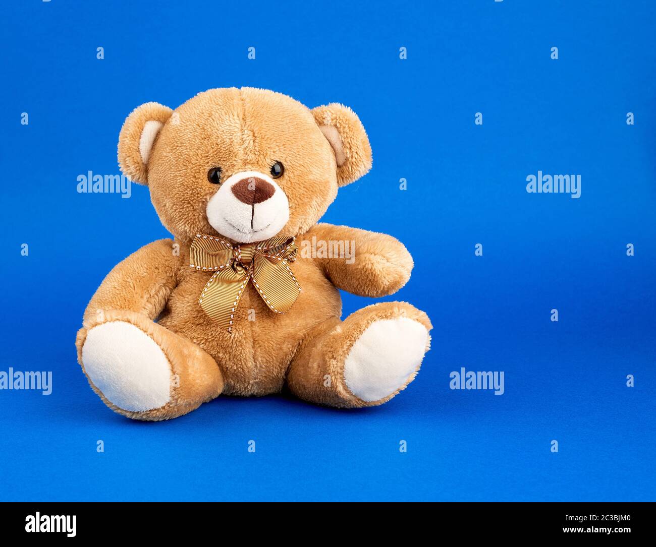 cute little brown teddy bear, toy is sitting on a blue background Stock ...