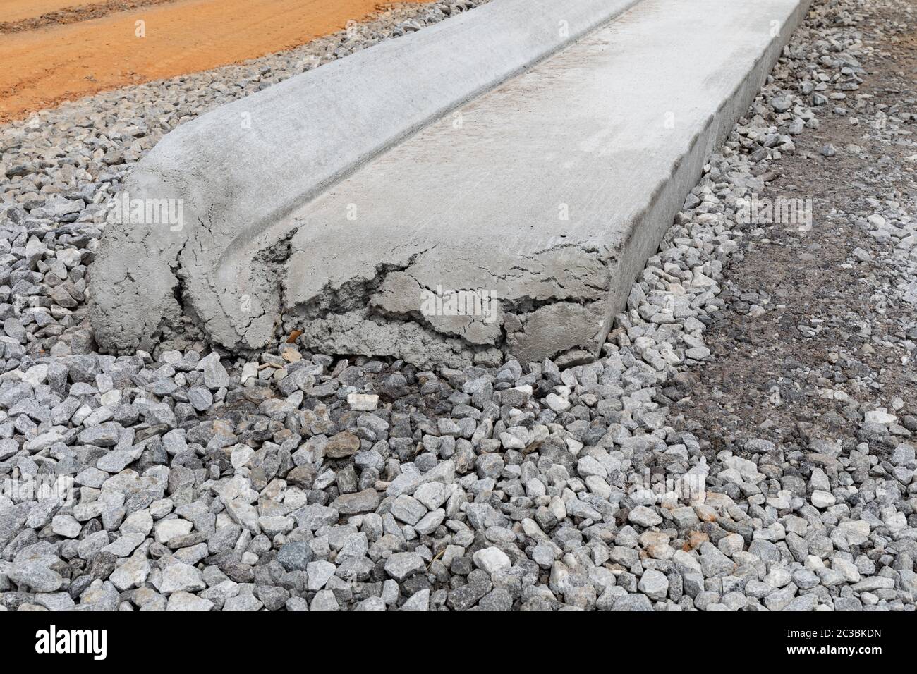 End of a section of rolled, extruded concrete curb alongside a road bed