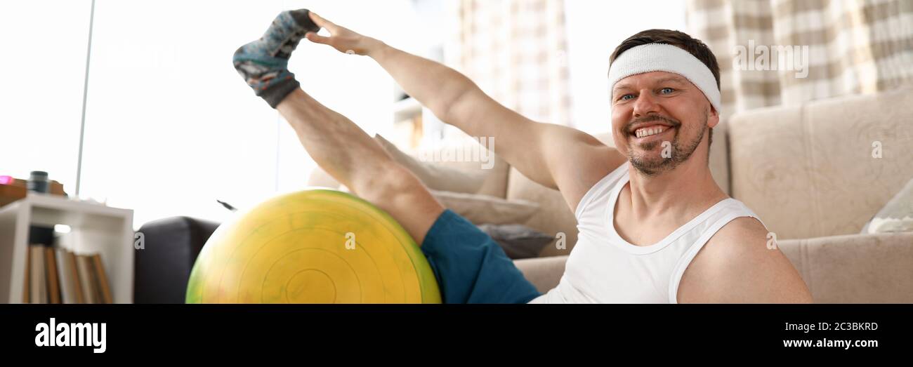 Man at home doing fitness with dumbbells and ball Stock Photo