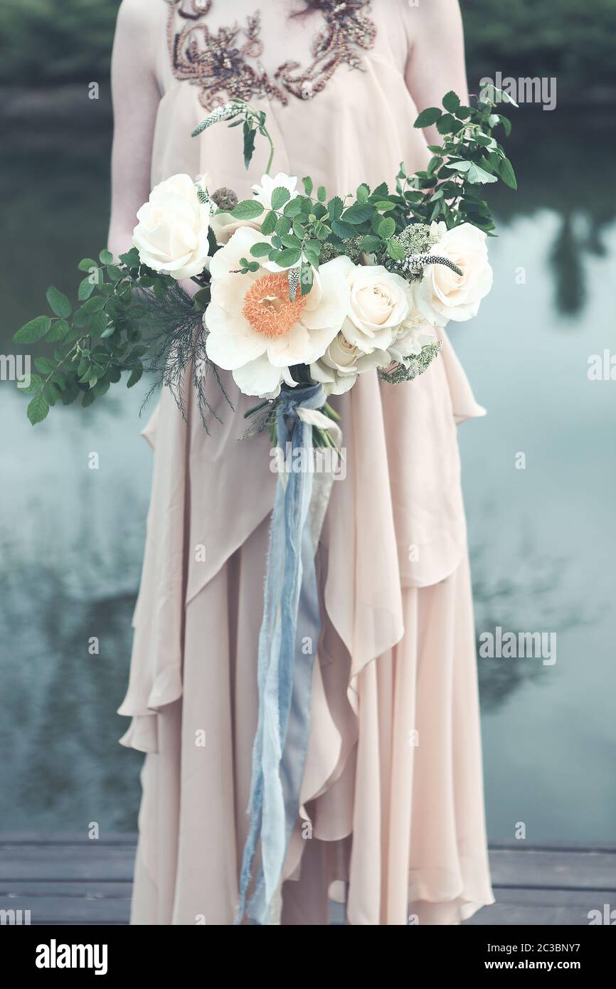 Woman in boho dress holding lush bouquet Stock Photo