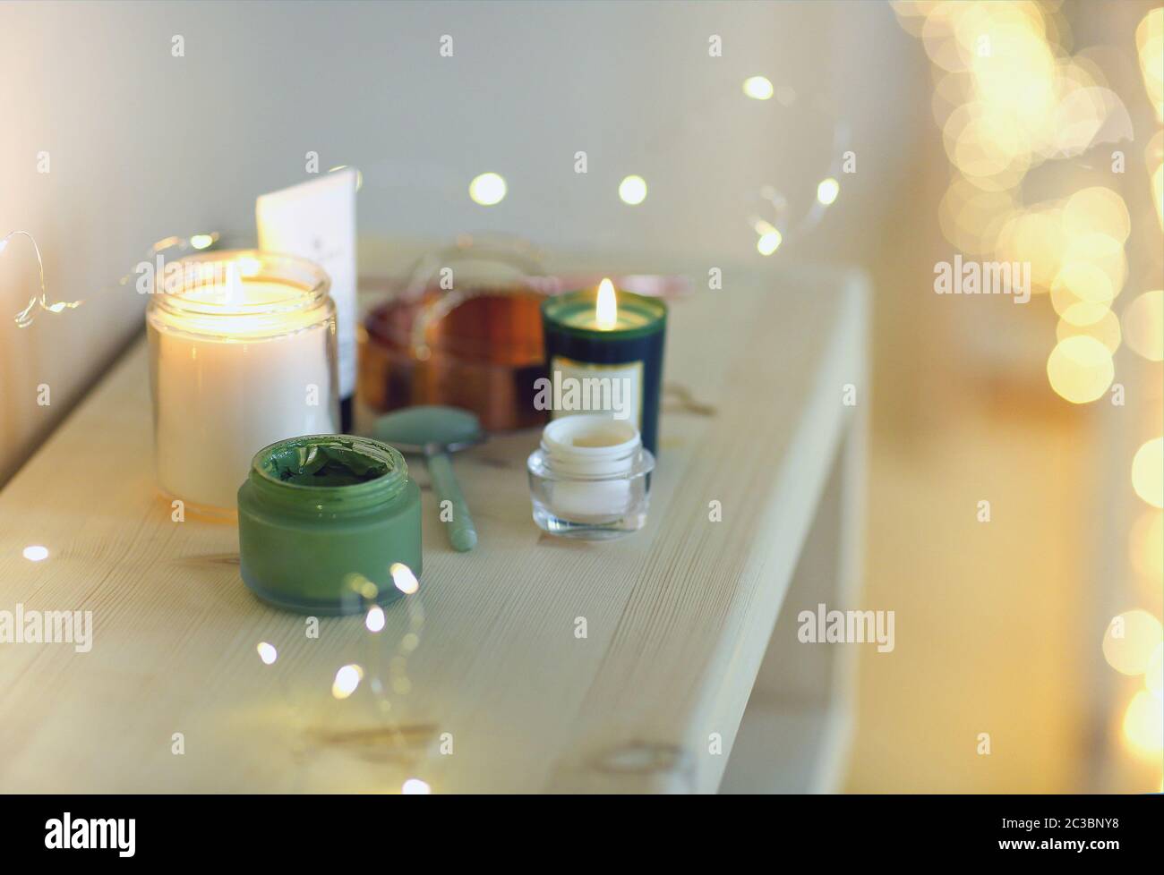 Burning candles and containers with various skincare cosmetics Stock
