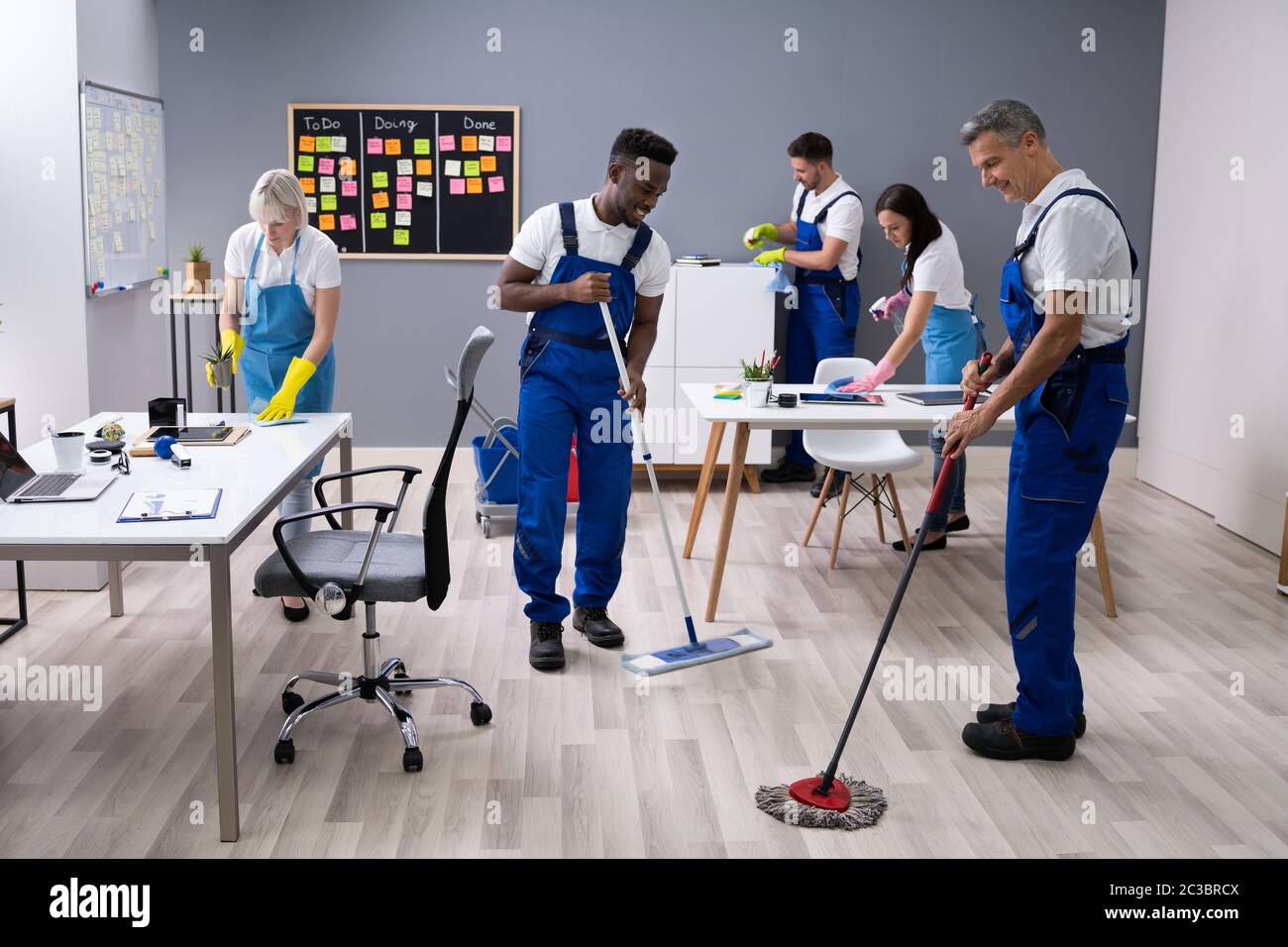 Group Of Janitors In Uniform Cleaning The Office With Cleaning