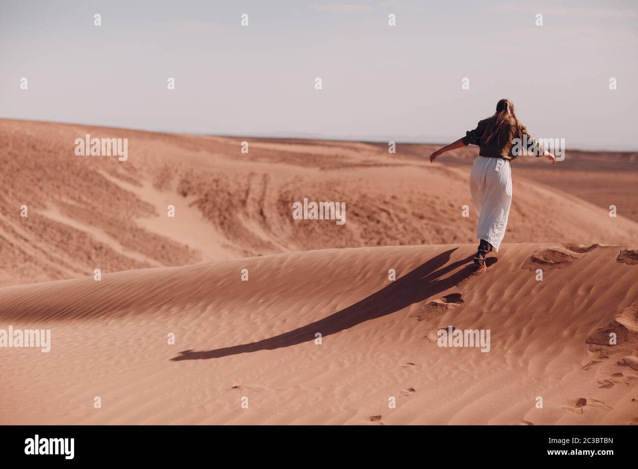 Young woman runs on sand dunes in desert Sahara Stock Photo - Alamy