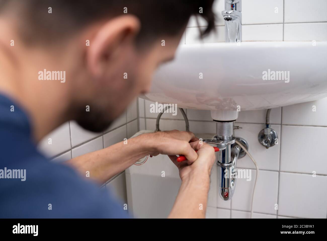 Young Plumber Fixing A Sink In Bathroom Stock Photo - Alamy