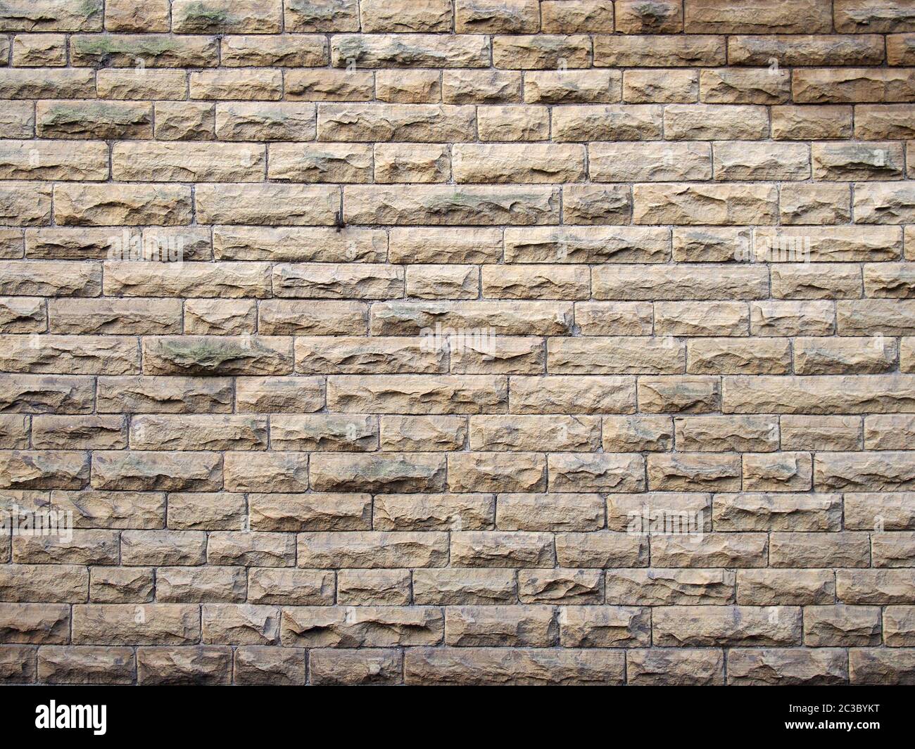 a full frame image of an old yellow sandstone wall made of regular blocks Stock Photo