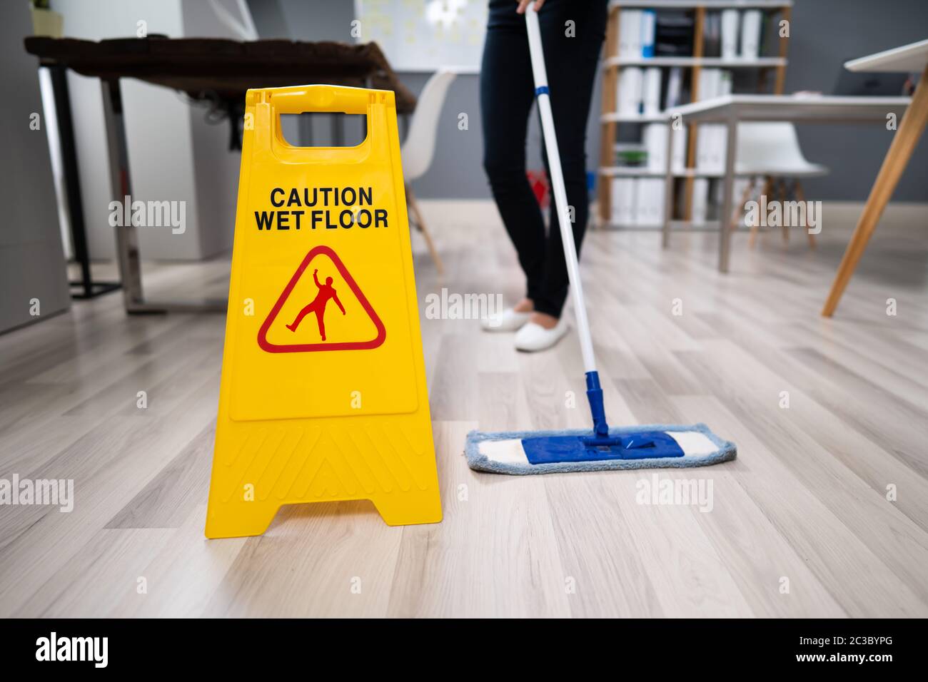 Female Janitor Mopping Floor In Modern Office Stock Photo