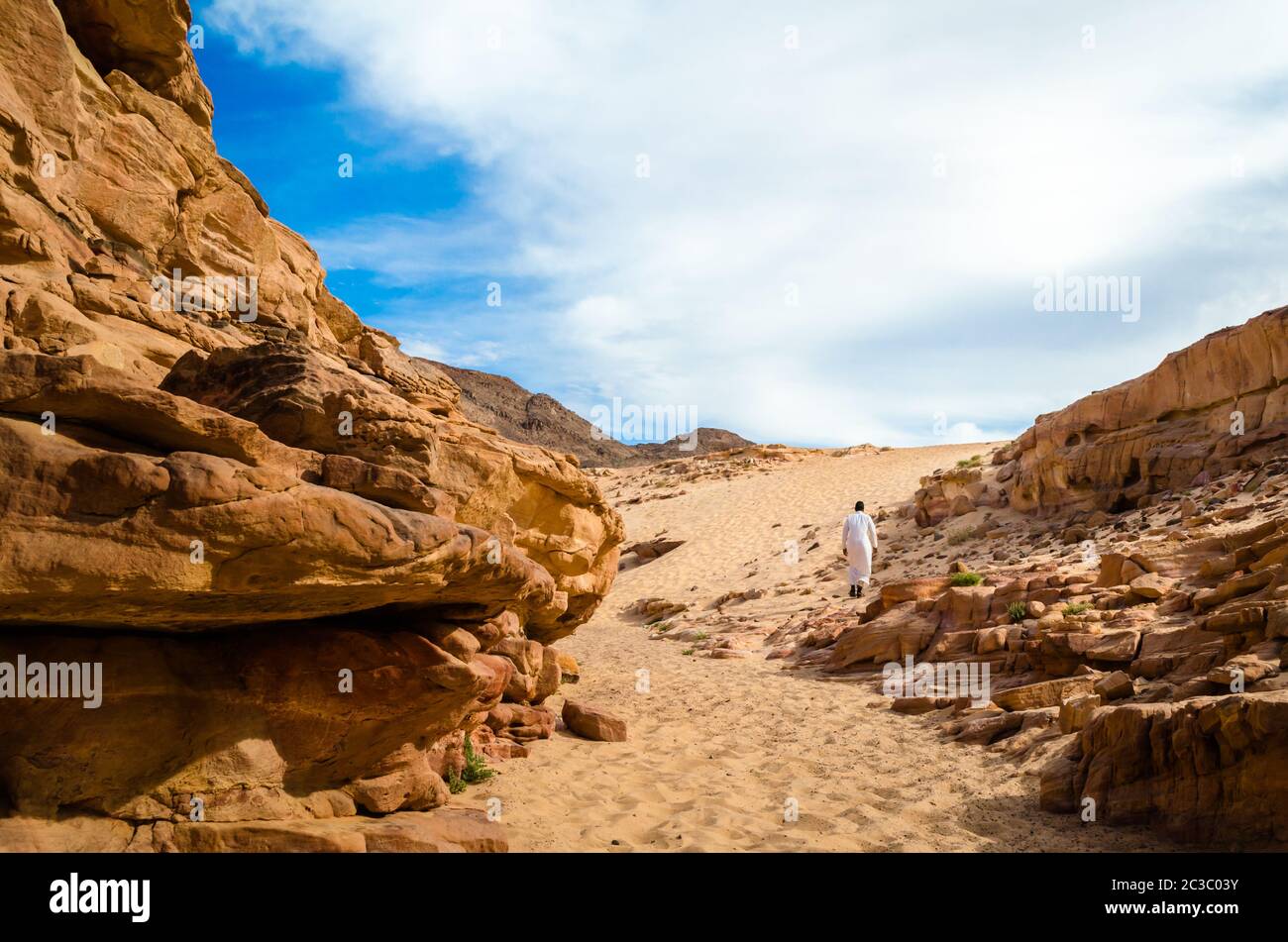 man in white arab clothing walks in a colored canyon in Egypt Dahab South Sinai Stock Photo