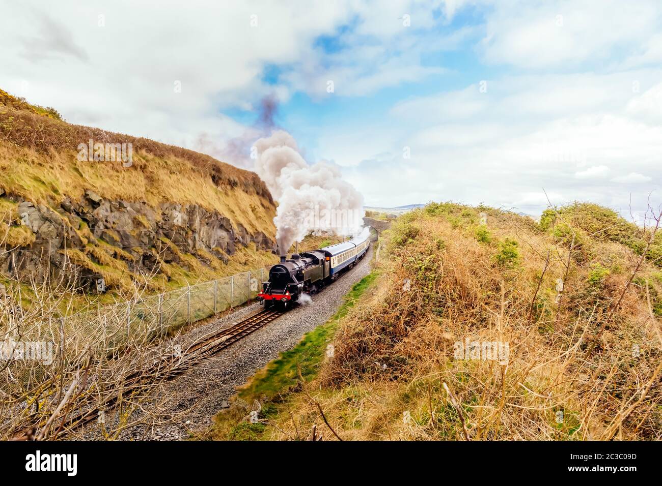 Large steam train or locomotive with passenger carriages on costal railway between Bray and Greystones, Ireland Stock Photo