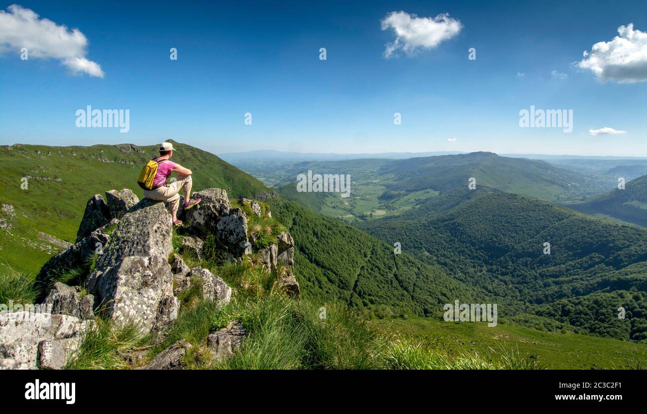 Hiker overlooking Cantal mountains, Auvergne Volcanoes Regional Nature Park, Cantal, Auvergne-Rhone-Alpes, France Stock Photo