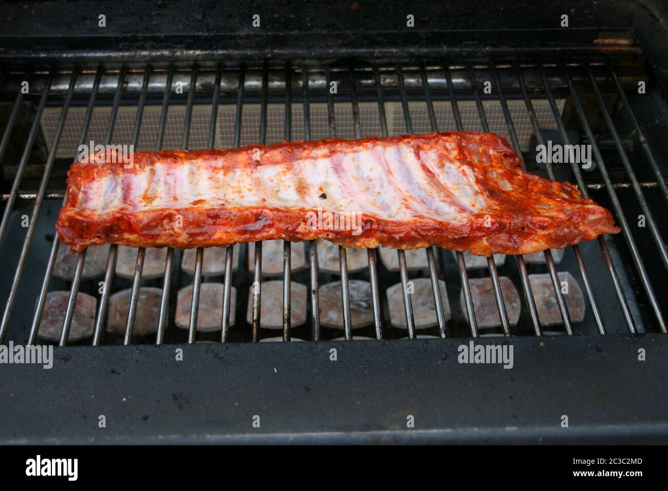 A large still raw piece of meat on a gas grill Stock Photo