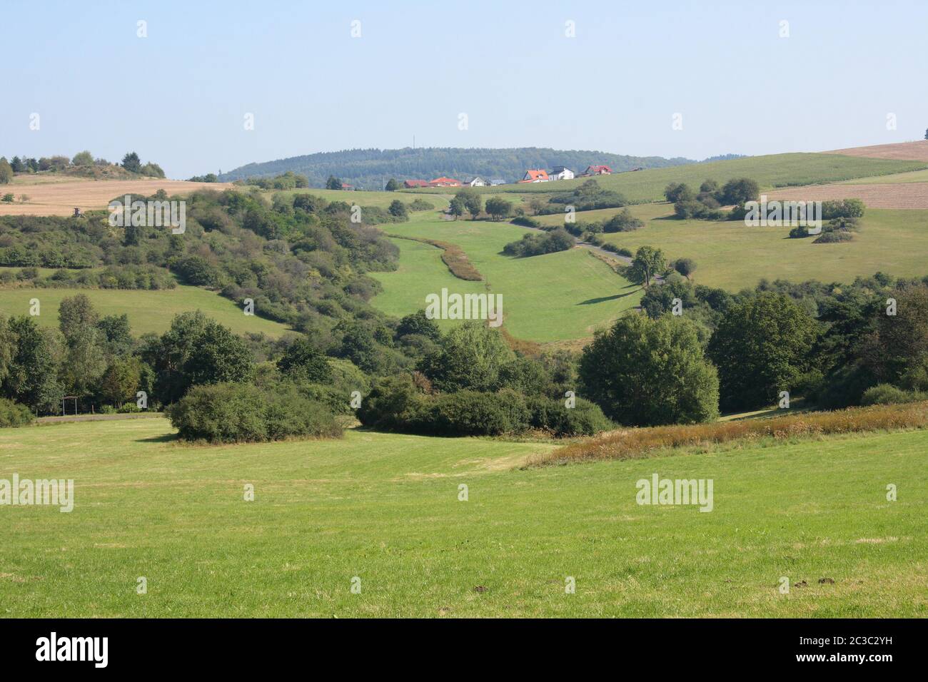 A hilly landscape with fields, meadows and forest Stock Photo