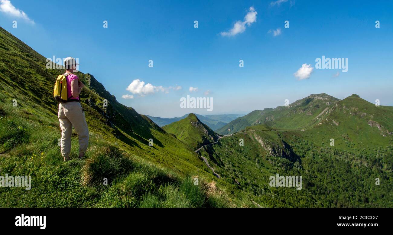 Hiker overlooking mountains, Auvergne Volcanoes Regional Nature Park, Cantal, Auvergne-Rhone-Alpes, France Stock Photo
