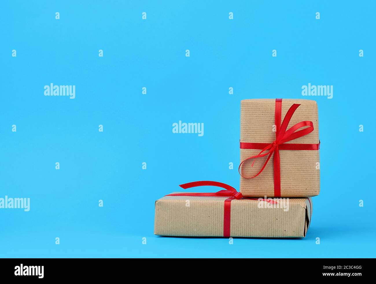 stack of boxes wrapped in brown paper and tied with a red bow, gifts on