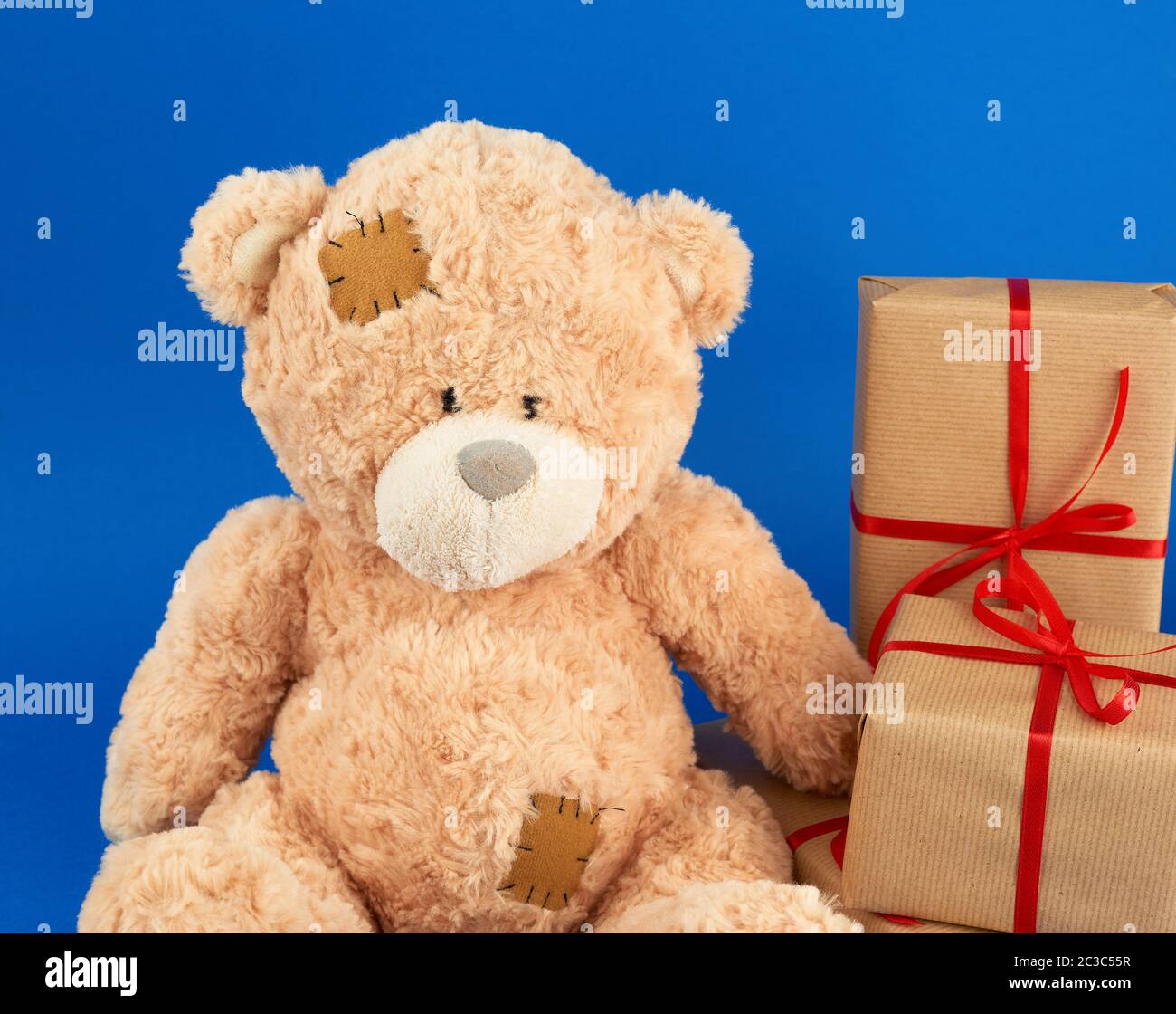 Cute Big Beige Teddy Bear Holds A Brown Box With A Red Ribbon On A Blue Background Festive Concept Stock Photo Alamy