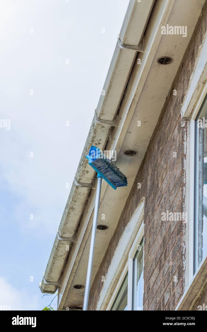 Brushing cobwebs and dust off guttering. Stock Photo