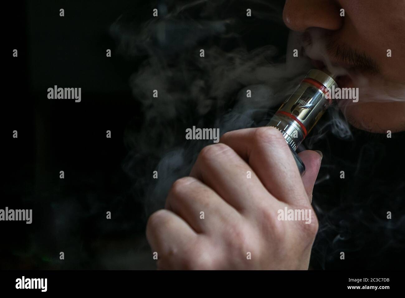 Man with concealed identity smoking a controversial vaping an electronic cigarette. Vaping is debatable in the health community if it is safe or a hea Stock Photo
