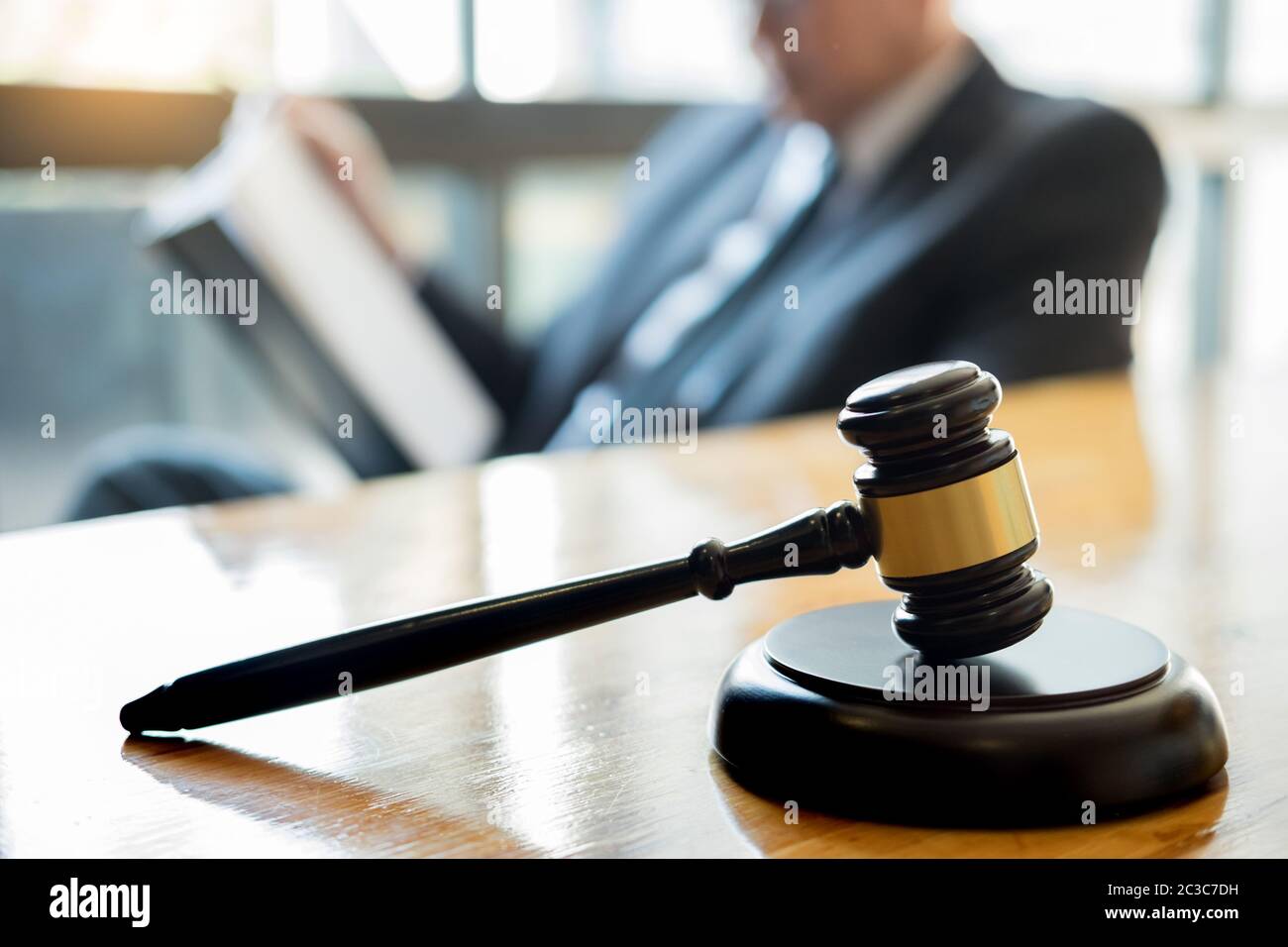 Male Lawyer Working With Contract Papers And Reading Law Book In A male-lawyer-working-with-contract-papers-and-reading-law-book-in-a