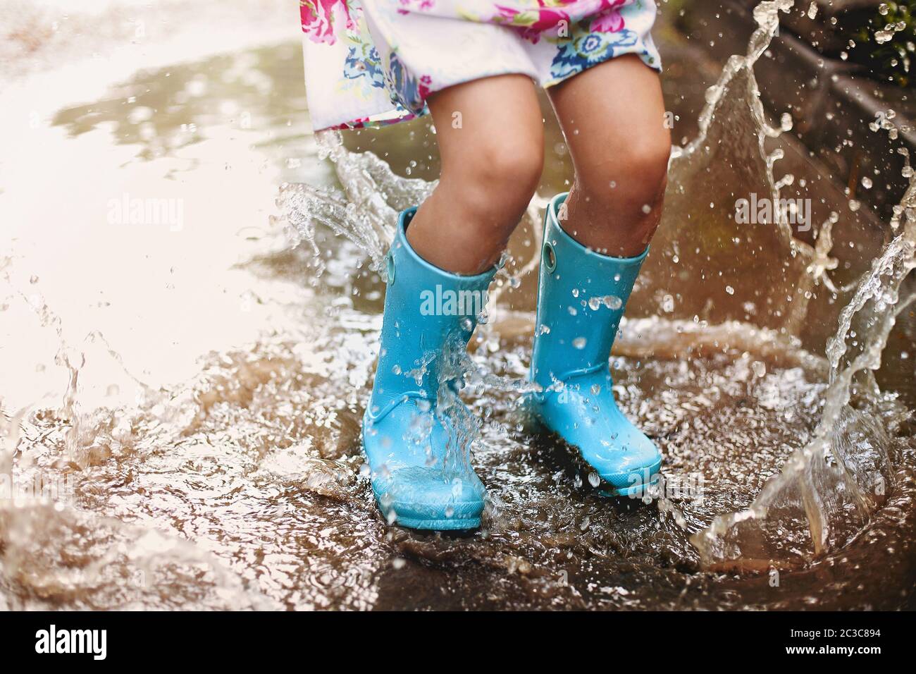 Cheerful small girl having fun in puddle on street Stock Photo - Alamy