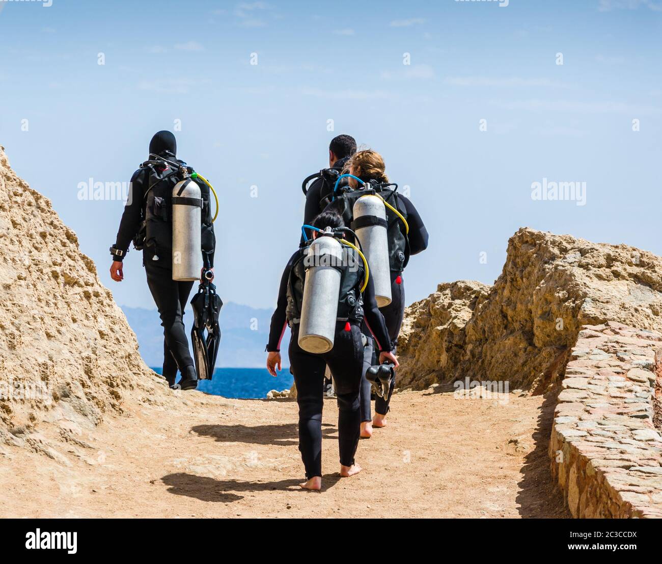 group of divers with equipment for diving go to the sea against the blue sky and clouds in Egypt Dah Stock Photo