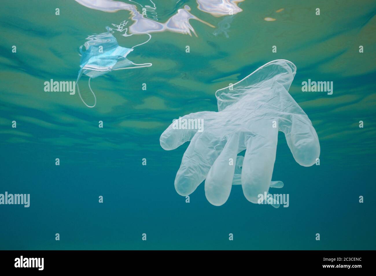 Glove and face mask underwater, ocean plastic waste pollution since coronavirus COVID-19 pandemic Stock Photo