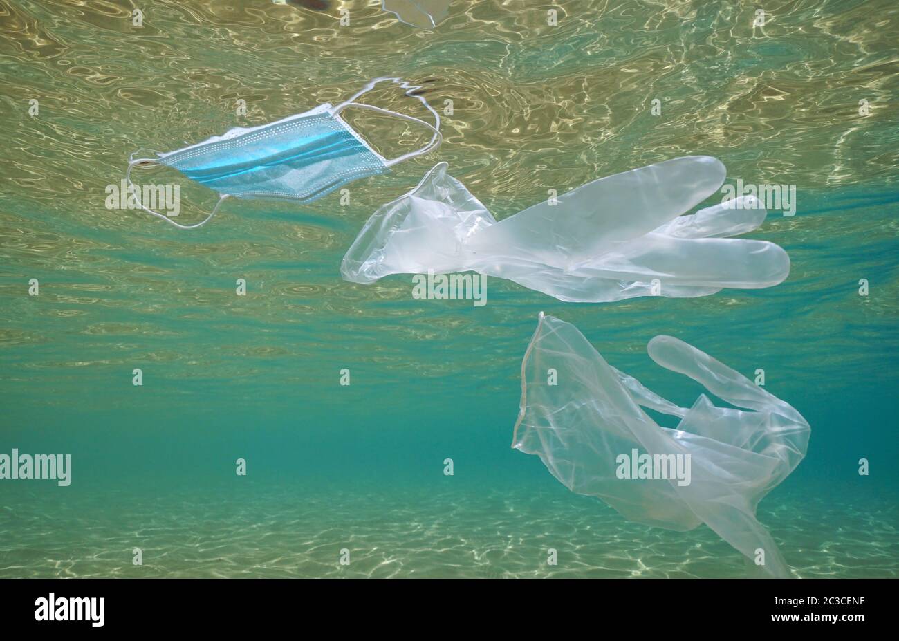 Gloves and face mask in the ocean, plastic waste pollution underwater since coronavirus COVID-19 pandemic Stock Photo