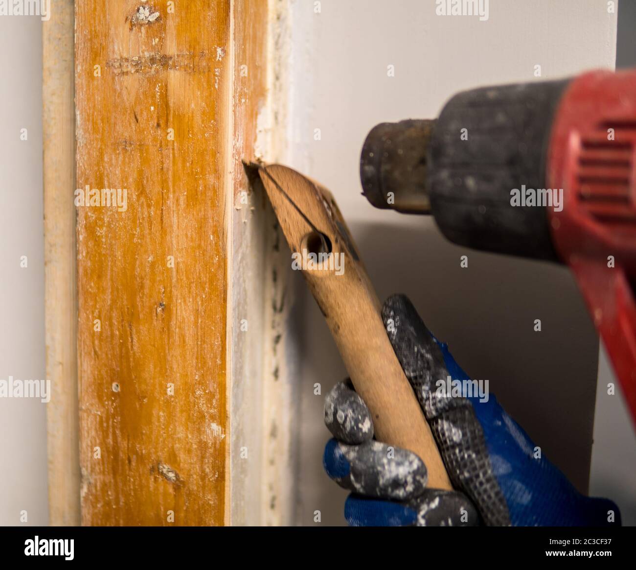 Detail of removing old white paint from door frame with heat gun and