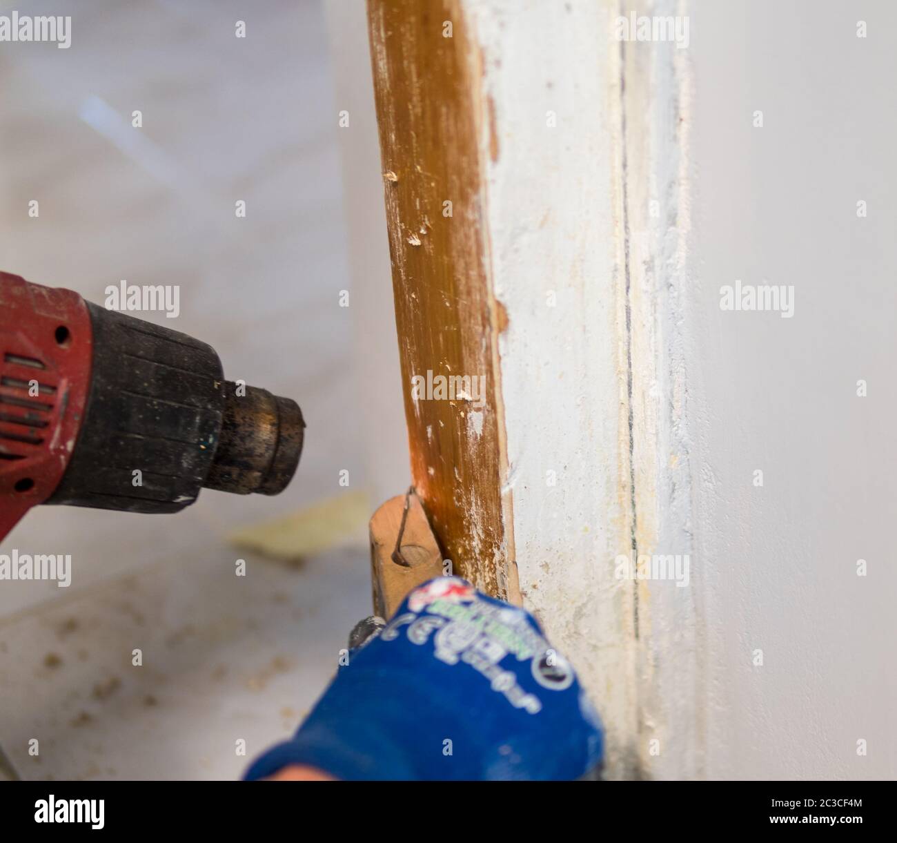 Detail of removing old white paint from door frame with heat gun and