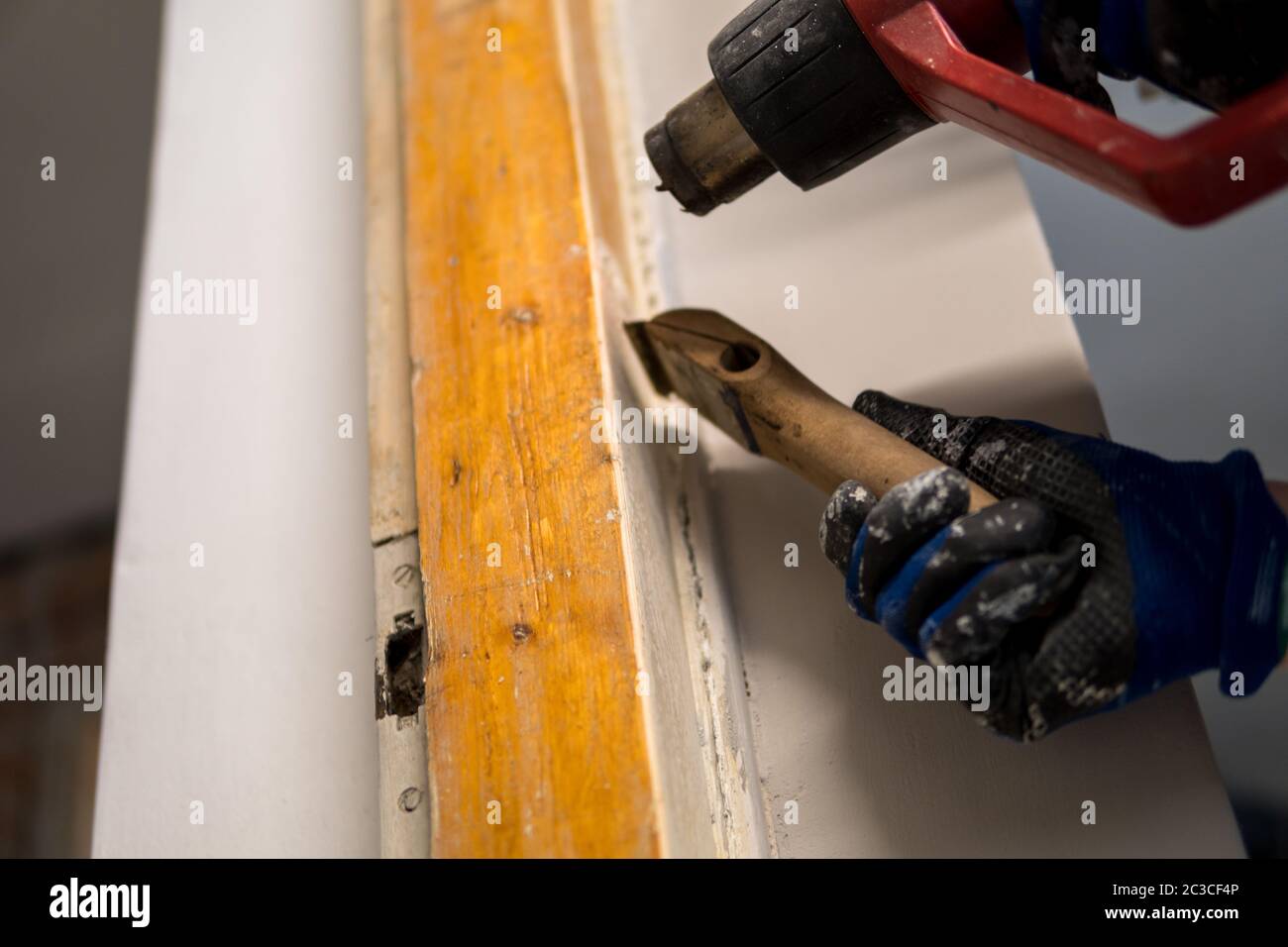 Detail of removing old white paint from door frame with heat gun and