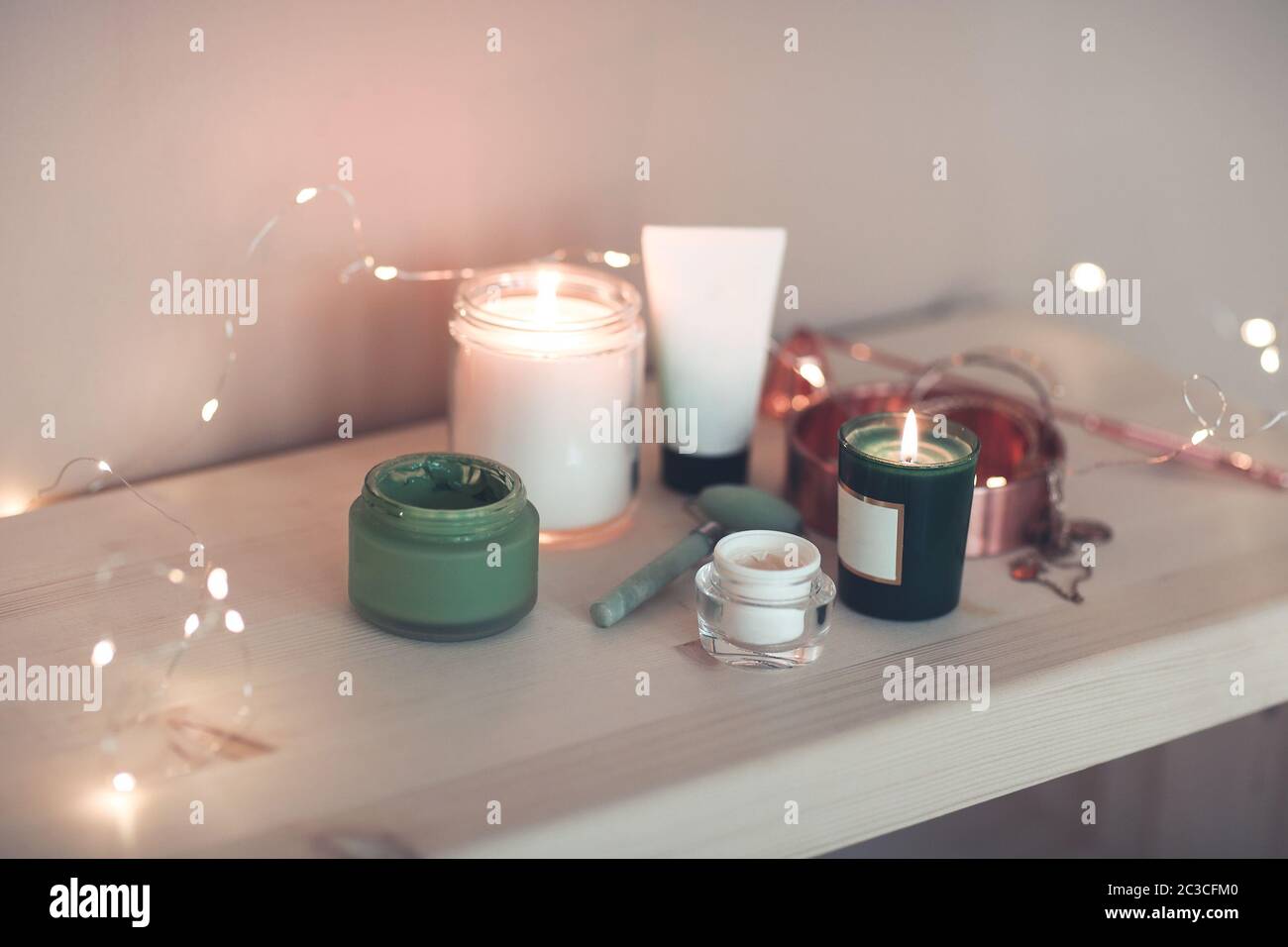 Burning candles and containers with various skincare cosmetics Stock