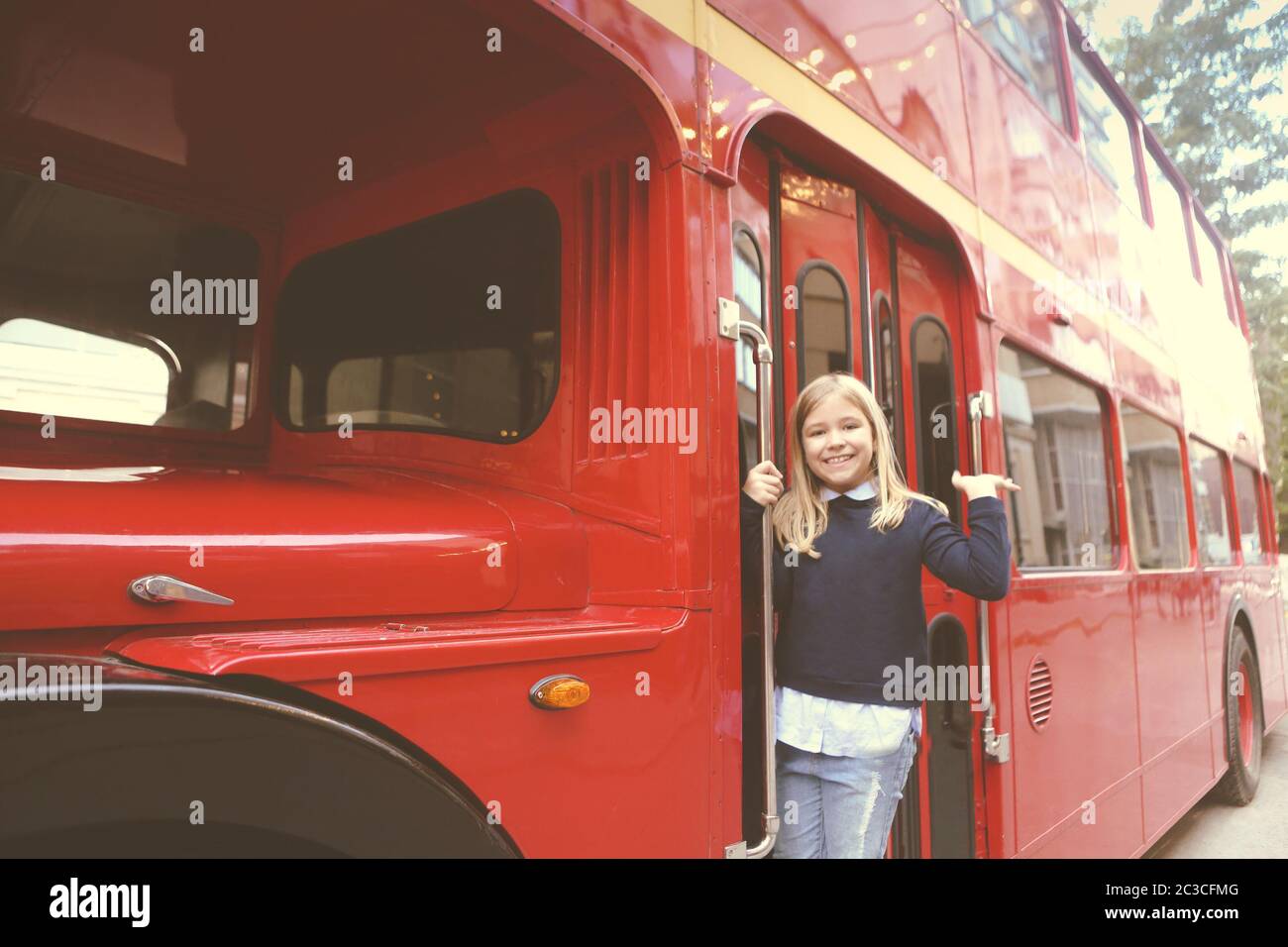 Preteen girl in entrance of red bus Stock Photo