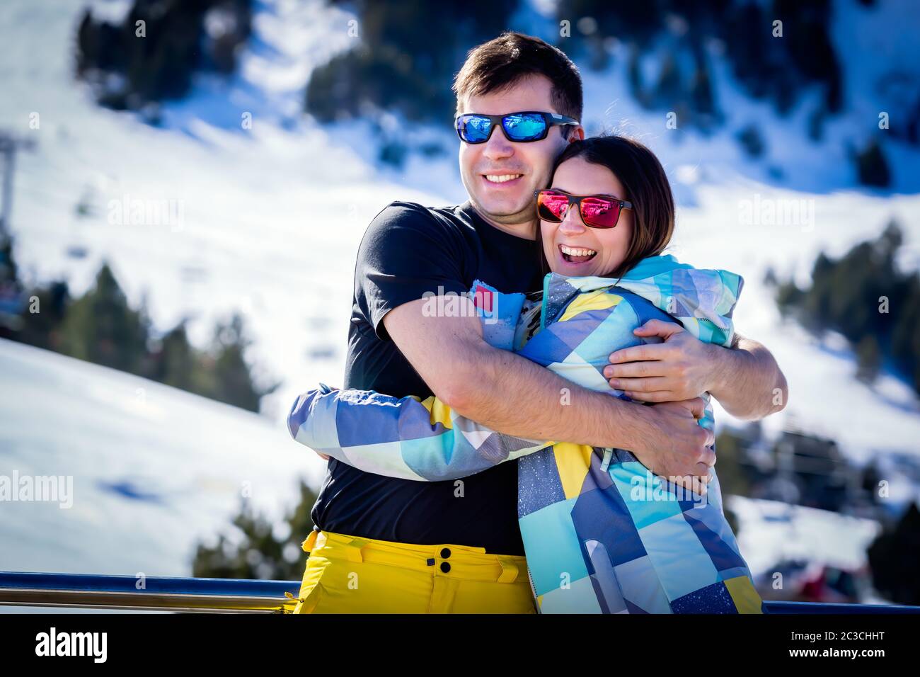 Couple, male and female, of skiers hugging and enjoying their winter holidays with winter background Stock Photo