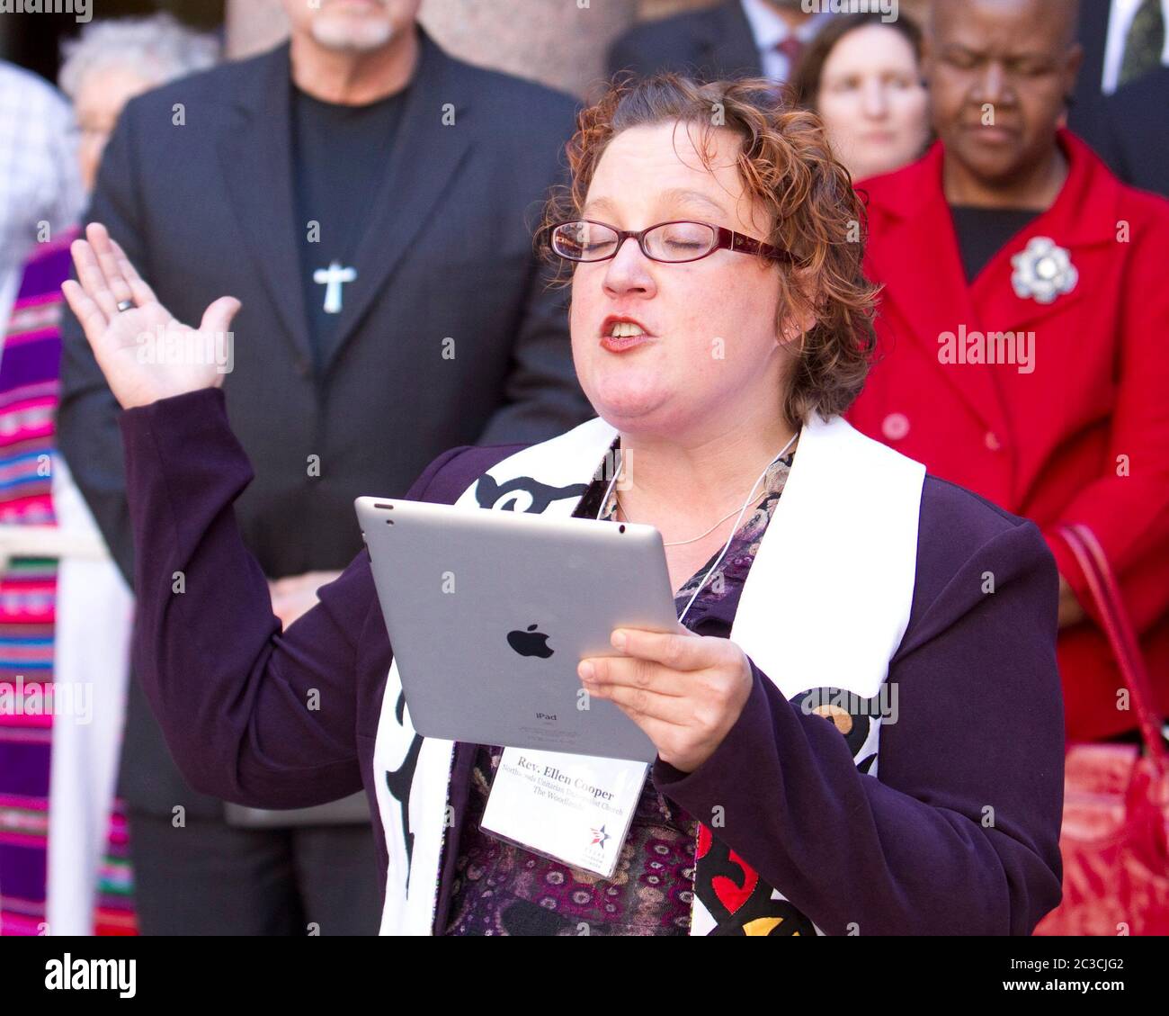 Austin, Texas USA, February 2013: Female minister, reading a prayer on iPad tablet computer, and other clergy members urge Texas legislators to restore funding for family planning and birth-control services for low-income women during a press conference at the Texas Capitol. Texas Faith in Action and the Texas Freedom Network are nonpartisan, grassroots organization of religious and community leaders. ©MKC/Bob Daemmrich Photography, Inc. Stock Photo