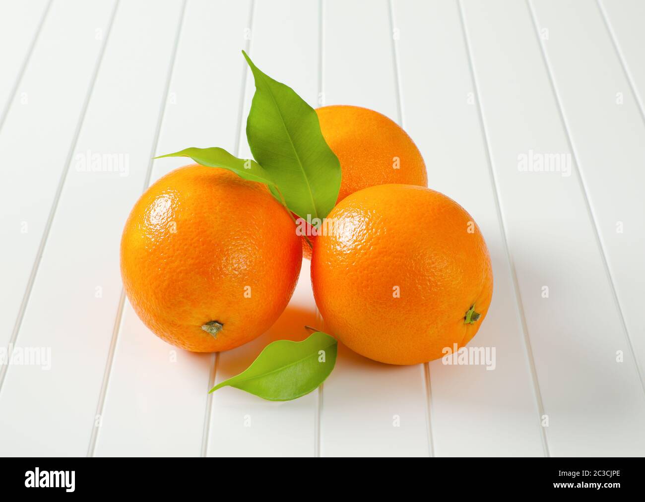 Three whole ripe oranges and leaves Stock Photo