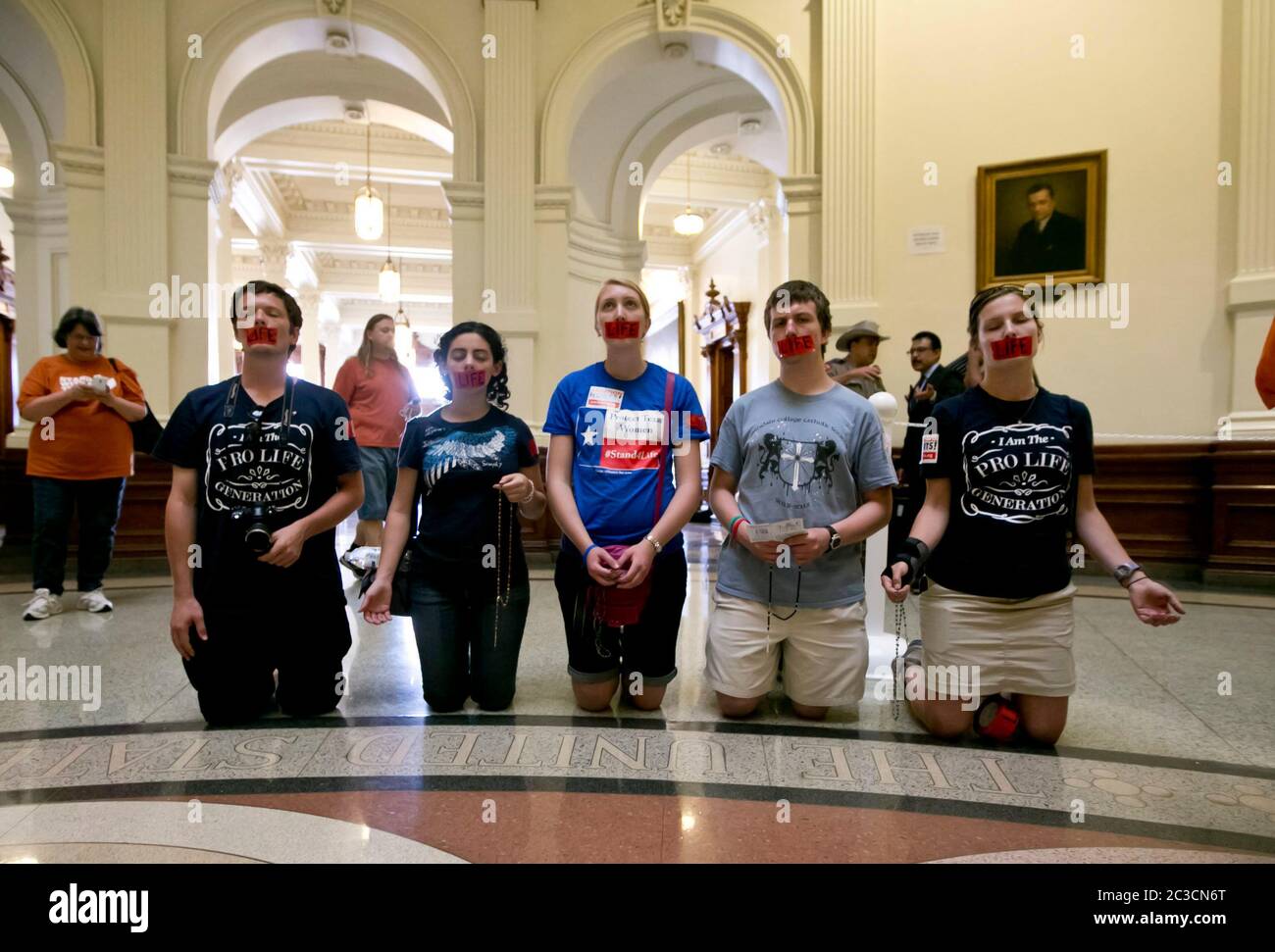 July 11, 2013 Austin, Texas USA: Abortion opponents, kneeling and with the word "life" taped over their mouths, pray during a pro-life rally at the Texas Capitol. Hundreds of pro-life and pro-choice supporters crowded into the building as state senators debated HB2, a controversial law putting tighter restrictions on women's access to abortions. The bill passed with a 19-11 vote, with all 18 Republicans and 1 Democrat voting yes. Earlier in the session, Sen. Wendy Davis's filibuster delayed action on the bill. ©Marjorie Kamys Cotera/ Daemmrich Photography Stock Photo