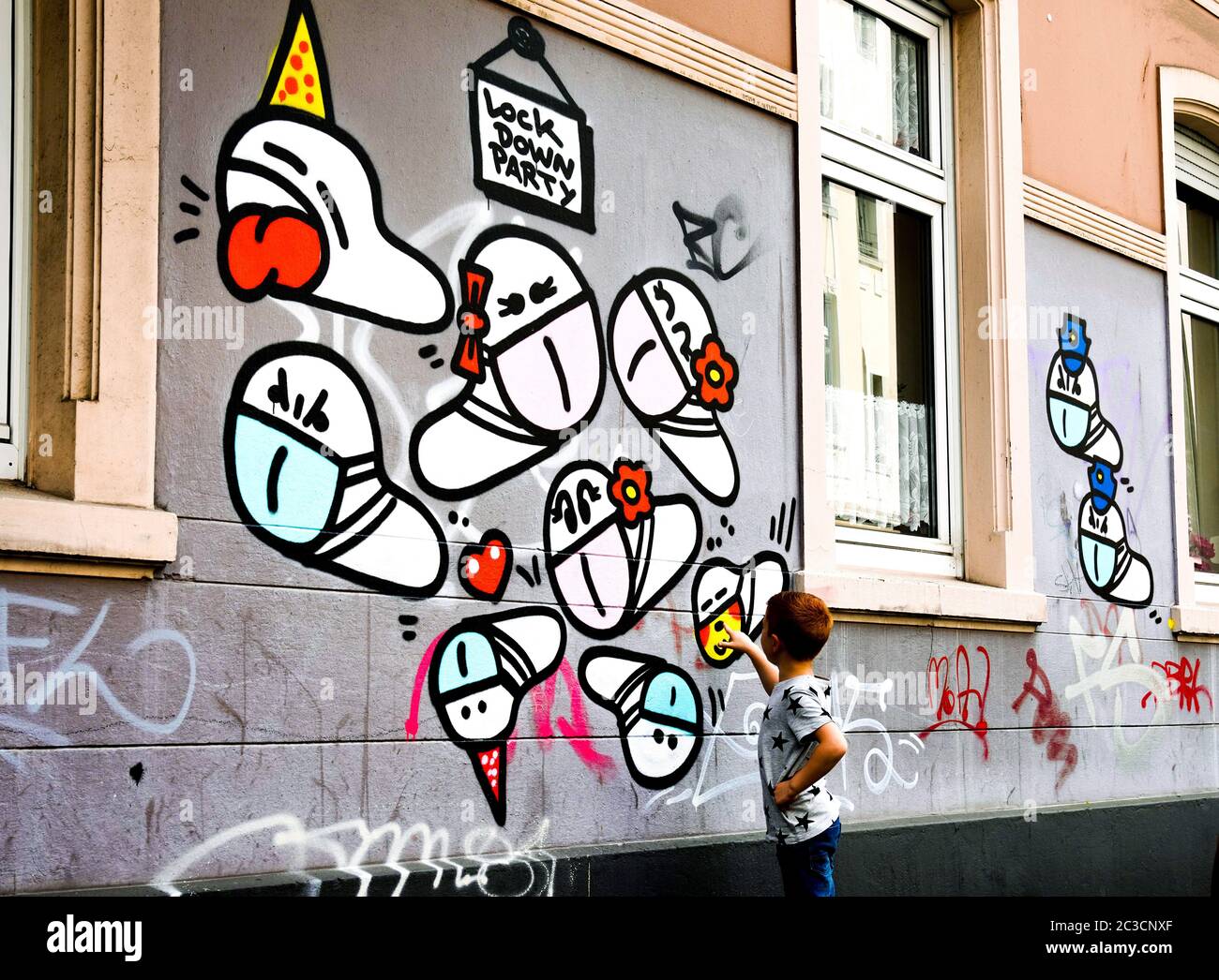 Dortmund, Germany, June 19th, 2020: Mask worms. Since the outbreak of the corona crisis in March 2020, small corona virus graffiti with a mouth mask created by an unknown sprayer can be seen on many house walls in Dortmund. --- Dortmund, 19.06.2020: Maskenwürmchen. Seit Ausbruch der Corona-Krise im März 2020 sind kleine Coronaviren-Graffitis mit Mundschutz eines unbekannten Sprayers an vielen Hauswänden in Dortmund zu sehen. Stock Photo