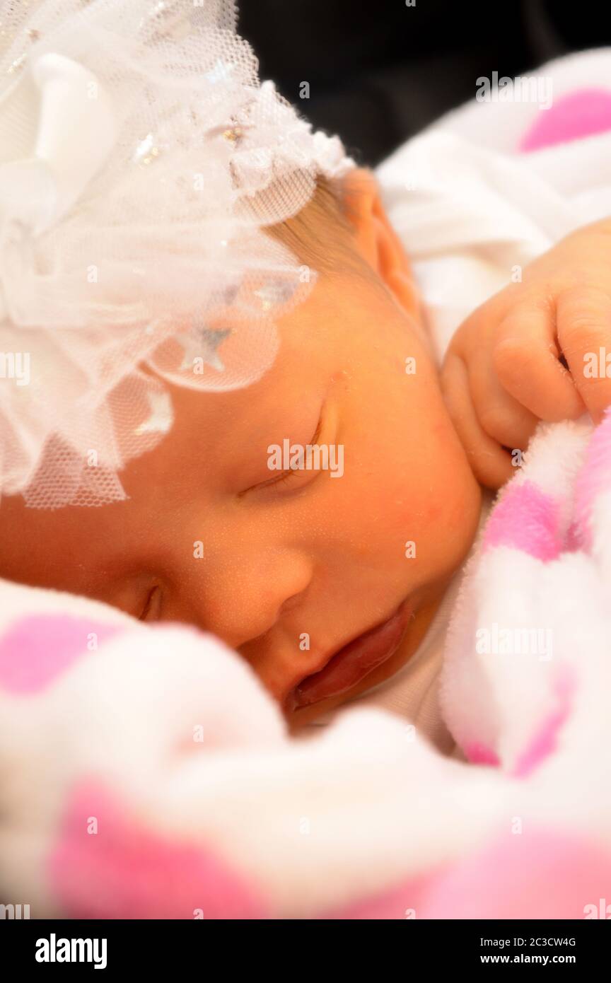 Closeup of a softly filtered focused new born baby girl who is gently drifted away in a sleepy cuteness. Stock Photo