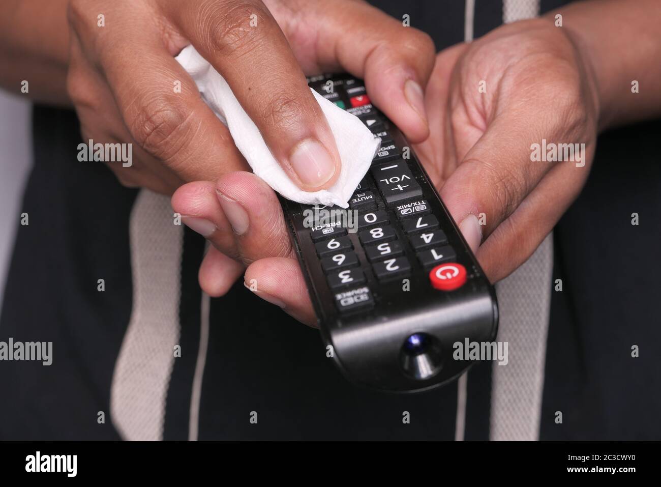 man hand cleaning TV remote controller with disinfectant wet wipe Stock