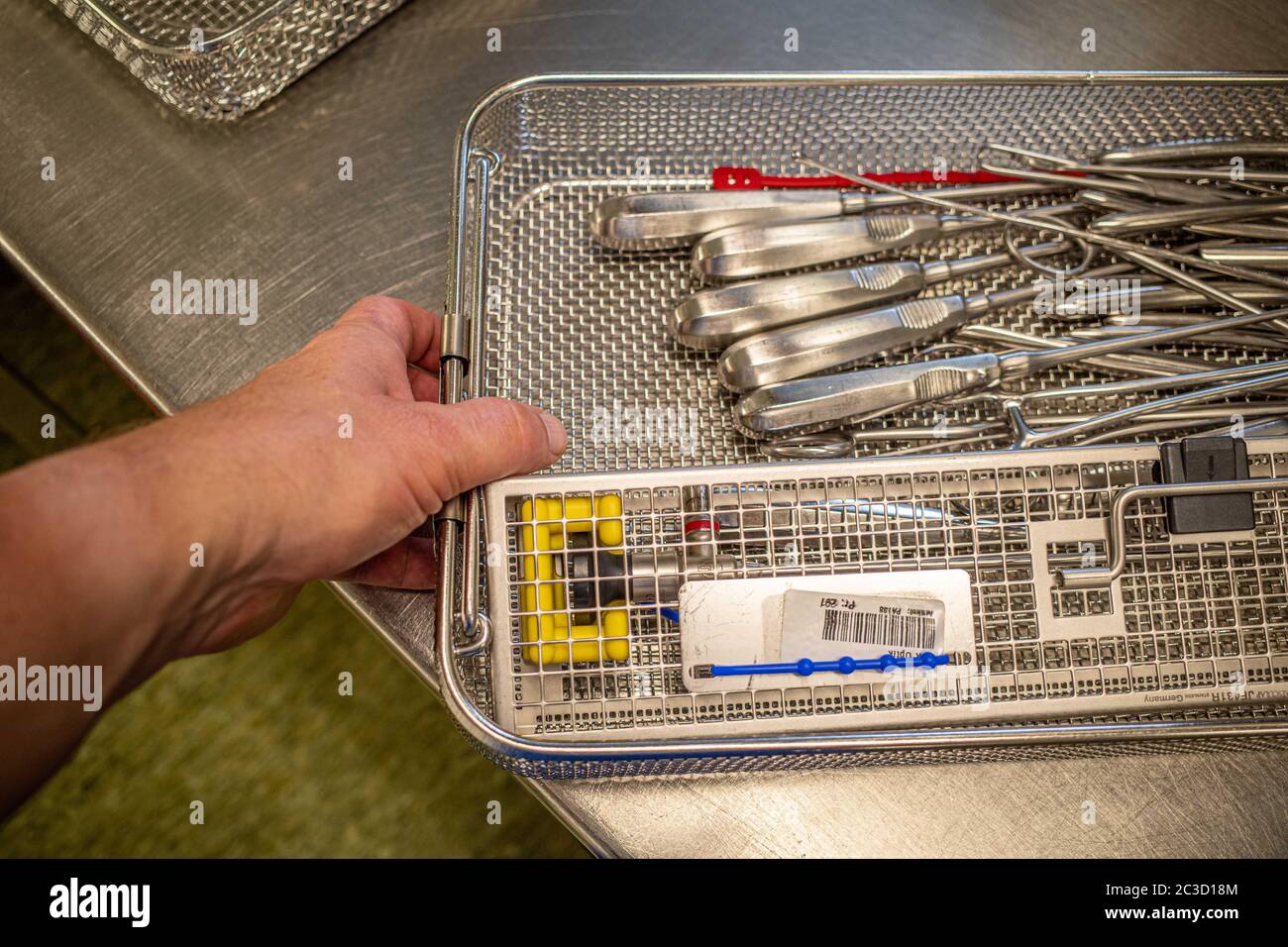 a hand reaches into a sieve with cleaned surgical instruments Stock
