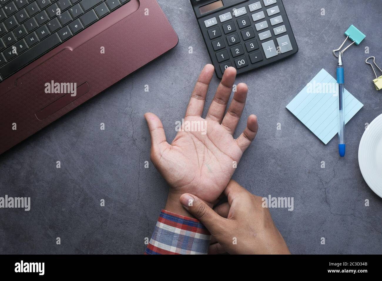 Young man in blue shirt suffering wrist pain  Stock Photo
