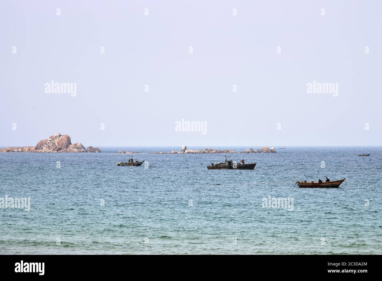 North Korea - May 4, 2019: Small island, two military boats carry out underwater work and fishing boat in Sea of Japan or East Sea Stock Photo